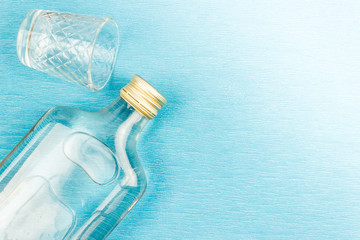Glass and flat glass bottle on a blue background. Alcoholic beverages, vodka.