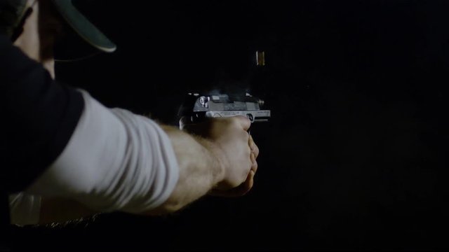 Hands holding a gun and firing two bullets, Ultra Slow Motion