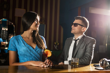 Handsome young man trying to start conversation with attractive young woman in a bar