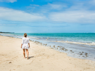 Fototapeta na wymiar attractive woman walking along beach view on a summer day
