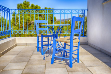 old greek blue chairs with wicker seating on a sun-drenched terrace at a vacation destination