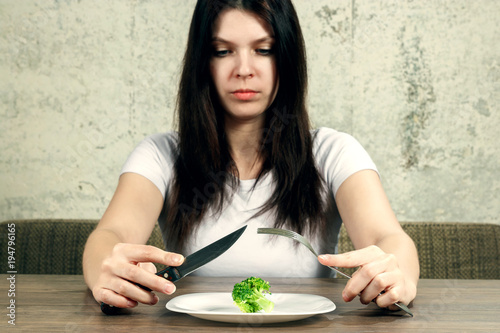 Sad Young Brunette Woman Dealing With Anorexia Nervosa Or Bulimia Sad Young Brunette Woman Dealing With Anorexia Nervosa Or Bulimia Having Small Green Vegetable On Plate