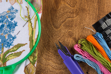 The process of cross-stitch. Canvas on hoops, needles, embroidery floss and pattern.