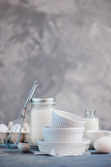 Baking forms in cooking concept with eggs, flour and milk on a concrete background. High key food photography with copy space.