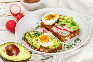Fototapeta na wymiar Toast with avocado, radish, egg and flax seeds