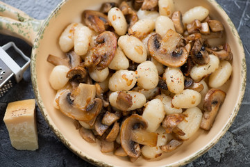 Close-up of boiled italian potato gnocchi with fried champignons and onion, top view, horizontal shot