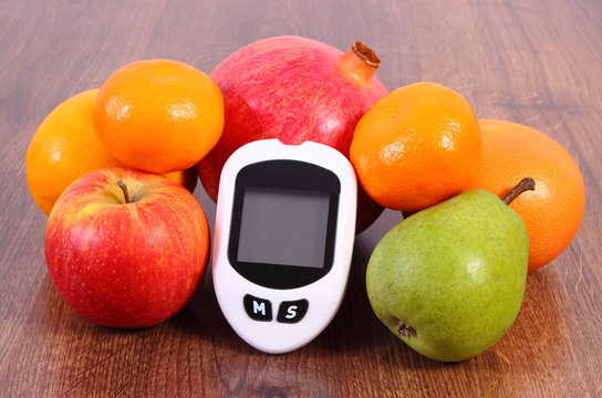 Glucose meter for checking sugar level with fresh fruits, diabetes and healthy nutrition concept