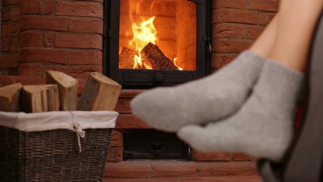 Woman feet resting in rocking chair, swinging - static camera, refocus from the flames to socks, closeup