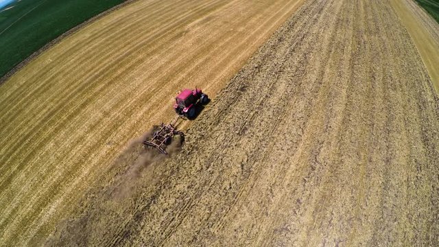 Tractor pulling land cultivating machine. Aerial footage.