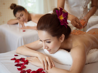 Obraz na płótnie Canvas Young Asian woman receiving salt massage in spa salon