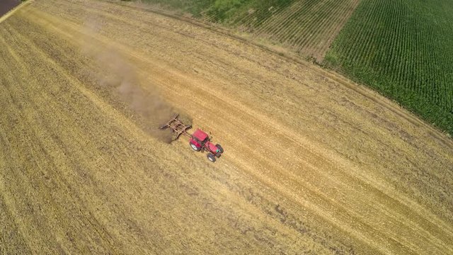 Tractor pulling land cultivating machine. Aerial footage.