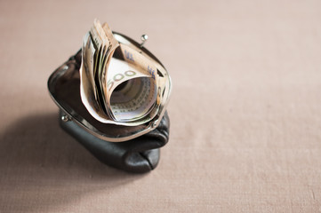 Ukrainian hryvnia in a vintage brown purse over brown tablecloth
