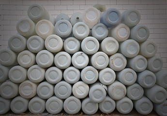 The white plastic water lined up in front of the white brick wall.