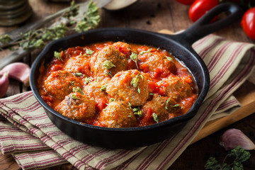 Meatballs in tomato sauce with dried oregano in a rustic vintage cast iron skillet