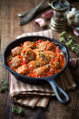 Meatballs in tomato sauce with dried oregano in a rustic vintage cast iron skillet