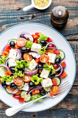 Greek salad of fresh cucumber, tomato, sweet pepper, lettuce, red onion, feta cheese and olives with olive oil. Healthy food, top view