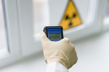 the scientist keeps a dosimeter in his hand to measure the level of radioactive contamination - obrazy, fototapety, plakaty