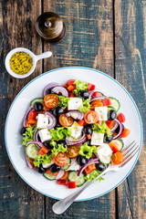Greek salad of fresh cucumber, tomato, sweet pepper, lettuce, red onion, feta cheese and olives with olive oil. Healthy food, top view