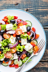 Greek salad of fresh cucumber, tomato, sweet pepper, lettuce, red onion, feta cheese and olives with olive oil. Healthy food, top view