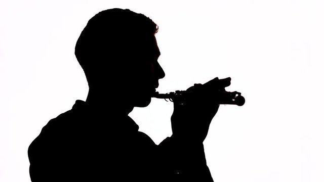 Silhouette. Isolated. The guy plays a beautiful melody on the flute. Profile of the musician. Copy space.