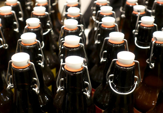 Rows Of Dark Glass Bottles With Lids As A Background