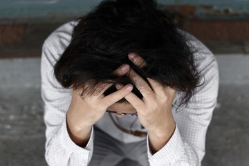 Fototapeta premium Aeriel view of confused anxiety young Asian business man covering face with hands.