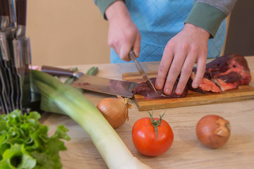 hands of a butcher cutting slices of raw meat off a large loin for tournedos