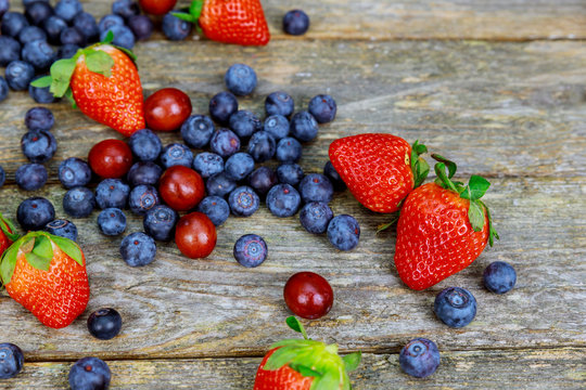 tasty summer fruits on a wooden table. Blueberries Grape Strawberries Blackberries