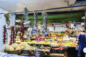 Porto, Portugal. August 12, 2017: Fruit and vegetable stall of the market called Do Bolhao with strings of garlic and chilli hanging from a bar and fruits in baskets
