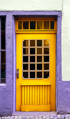 Wooden yellow beautiful door in an old lilac, white colored building