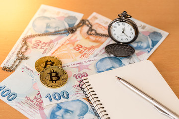 Journal, pen, pocket watch, and two golden bitcoins on turkish liras