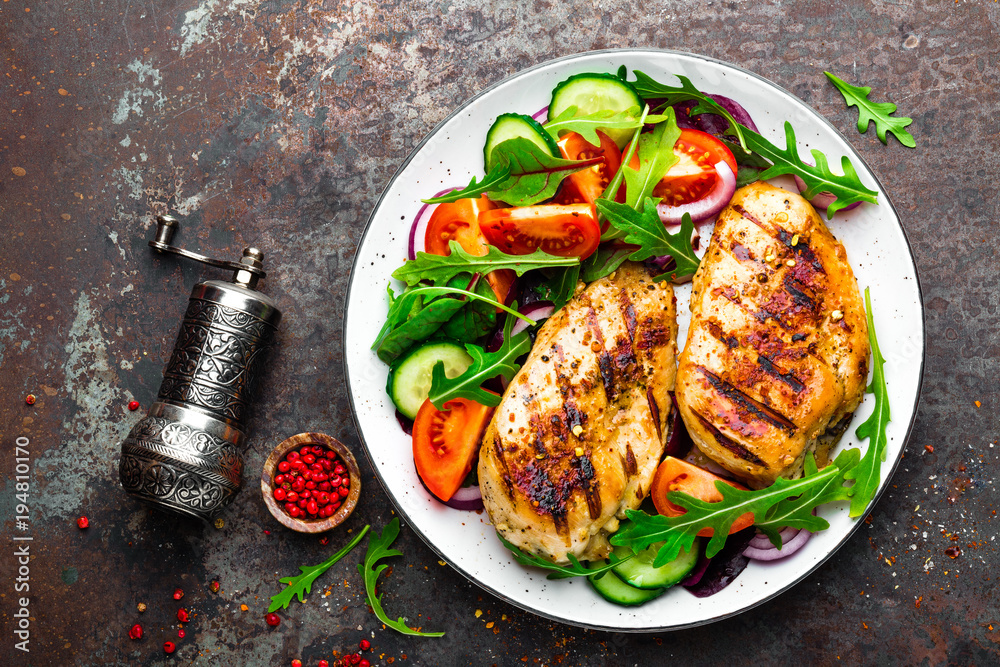 Sticker grilled chicken breast. fried chicken fillet and fresh vegetable salad of tomatoes, cucumbers and ar