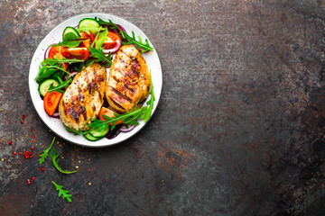 Grilled chicken breast. Fried chicken fillet and fresh vegetable salad of tomatoes, cucumbers and...