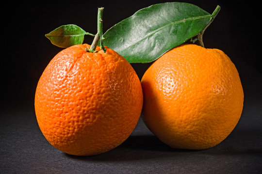 Two ripe oranges on black background