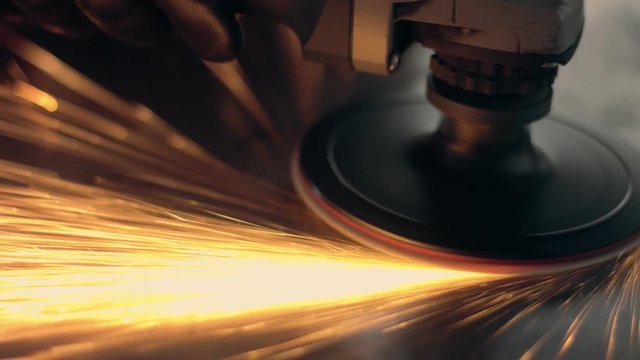Worker using industrial grinder. Worker in garage makes work with metall and grinder. Slow motion how flying sparks