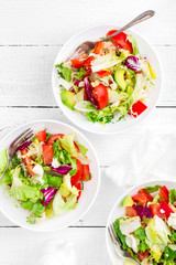 Healthy vegetable salad with fresh greens, lettuce, avocado, tomato, seet pepper and  goat cheese. Delicious and nutritious diet dish for breakfast. Salad bowls on white wooden background