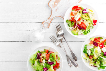 Healthy vegetable salad with fresh greens, lettuce, avocado, tomato, seet pepper and  goat cheese. Delicious and nutritious diet dish for breakfast. Salad bowls on white wooden background