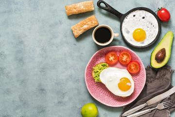 Breakfast. Fried egg with avocado and tomatoes on a blue background. Copy space, top view. The concept of healthy eating.