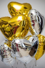 Close-up of balloons in the shape of heart on a white background. Helium balloons. Gold and silver.