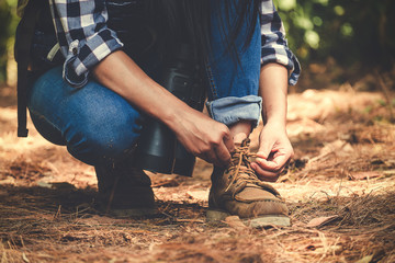 Closeup image of a man tying shoelace while trekking in a tropical forest