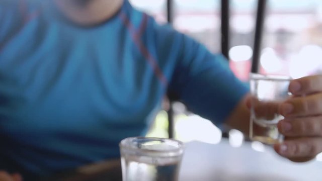 Three men clink with glasses of vodka in cafe. slow motion. 3840x2160