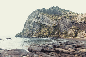 Famous Seongsan mountain on a windy day at the shore of Jeju Island - South Korea