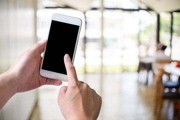 Smartphone on hand in the cafe with empty screen of mobile.