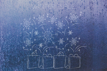winter sales shopping bags with snowflakes falling over frost background