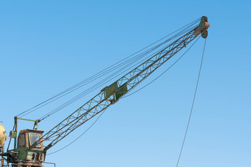 Fototapeta premium Old unused crane close up shot on beautiful blue sky background.
