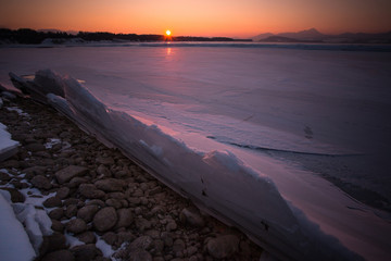Frozen lake with icebergs at sunset