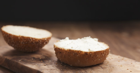 cream cheese on sesame bun on wood board