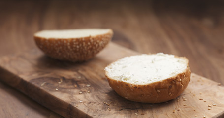 cream cheese on sesame bun on wood board