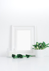 White frame desktop with yellow-green leaves in tiny cup and candle