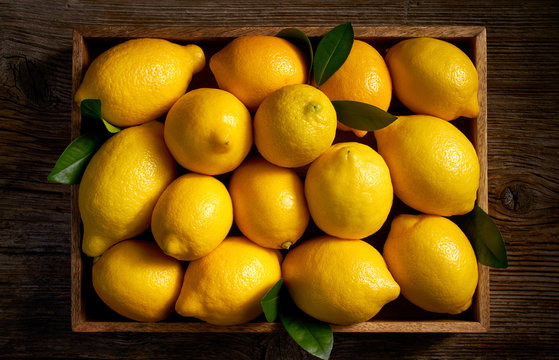 Fresh lemon fruits in a wooden box  on a wooden rustic table, top view   